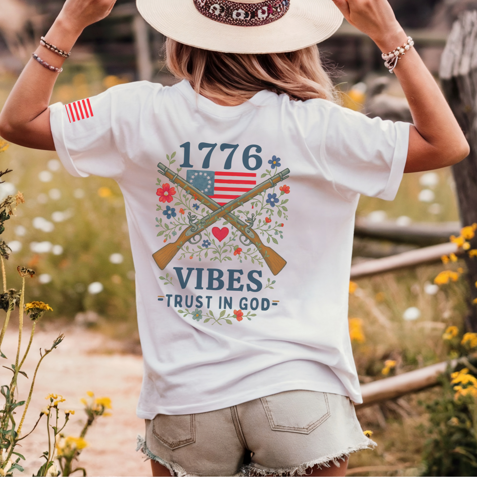 woman wearing a white t-shirt with patriotic design crossed muskets floral adorned with a betsy ross flag trust in god text
