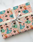Gift wrapped in retro-themed paper featuring poodle skirts, jukebox and records, against a pink background.
