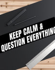 Black mat with 'KEEP CALM & QUESTION EVERYTHING' text, pen, and ruler on a wooden surface