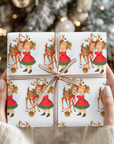 Christmas-themed gift wrap with reindeer and little girl kiss on a white background beneath the christmas tree