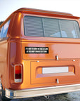 Orange vintage van with a humorous sticker on the back