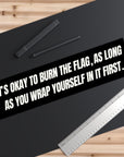 Black bumper sticker with white text on a black surface with a ruler and pen.