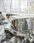 Gift boxes wrapped in scenic vintage estate paper with strolling figures and large manors.