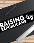 Sticker with 'RAISING REPUBLICANS' text on a black background with a ruler and pen.