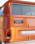 Orange van with a humorous sticker on the back