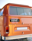 Orange vintage van with a humorous sticker on the back