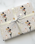 Gift wrapped in wedding-themed paper with a retro bride and groom and cake design on a marble surface.