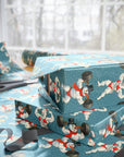 Gift boxes wrapped in blue paper with a humorous snowman design lifting weights, on a blue background.