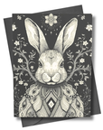 Greeting card with a detailed black and white rabbit illustration on a dark background with floral elements.