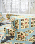 Whimsical Christmas dollhouse pattern with garlands and golden stars on dusty blue gift wrap.