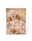 Dog in a robe with a towel on its head, holding a glass of champagne, on a white background.