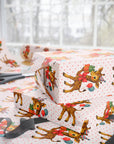 animal theme wrapping paper for childrens birthdays featuring a giraffe wearing a party hat with balloons and presents on dotted background