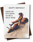 Birthday card with a cowboy riding a bull and text 'Happy Birthday, hang on it's going to be a wild year.'