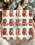 Gift wrapped in paper with Highland cow pattern held by hands against a blurred Christmas tree background