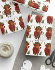 Gift wrap with Highland cow pattern on a white surface with scissors and yarn.