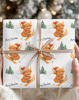 Christmas wrapping paper featuring a highland cow in a santa hat skiing down a snowy hill, set on a white background.