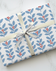 Christmas wrapping paper featuring red white and blue holly-pattern.