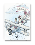 Vintage wedding greeting card with bride and groom flying in a biplane with Just Married banner trailing behind.
