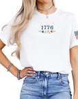 Woman wearing a white t-shirt with a graphic design 1776 and floral elements front view