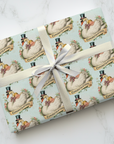 Gift wrapped in congratulatory swan and baby patterned wrapping paper with a white ribbon on a light background.