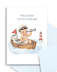 Greeting card with illustration of a baby boy in a sailor outfit with a teddy bear and lighthouse, text 'Welcome Little Sailor'.