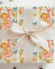 Gift box with baby-themed wrapping paper and a white ribbon on a white background with star decorations.