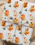 Christmas wrapping paper featuring a Pomeranian, Westie, cavalier, Golden Retreiver, and playful fox skiing down snowy slopes in Santa hats.