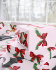 Christmas-themed wrapping paper with red bows and green garland on a pink background side view