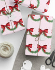 Christmas-themed wrapping paper with red bows and green garland on a pink background front