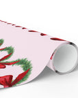Roll of Christmas-themed wrapping paper with red bows and green garland on a pink background