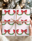Gift box with Christmas design of red bows and green garland held by hands against a blurred Christmas tree background