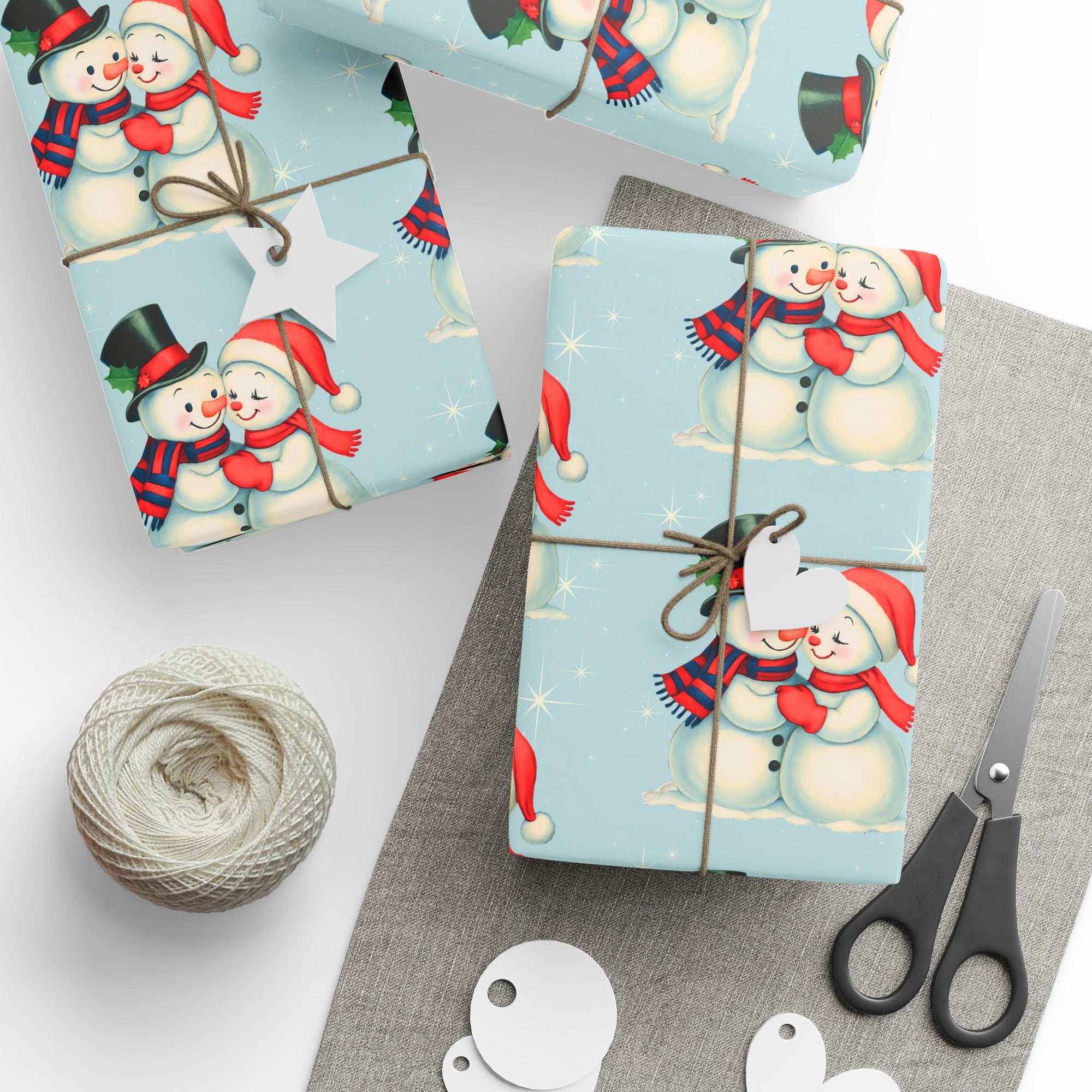 Gift wrapped in Christmas themed wrapping paper with snowmen couple on a blue background and sitting on a table