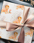 Gift wrapped in vintage-style baby-themed paper with a pink ribbon.