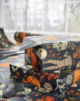 Halloween-themed gift wrap with skeletons, pumpkins, and mummies on a dark background