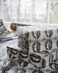 Stack of wrapped presents with black and white patterned paper, scissors, and ribbons on a matching surface.