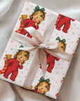 Gift wrapped in paper with a child and teddy bear pattern, tied with a beige ribbon.