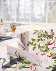 Vintage mistletoe wrapping paper with green leaves and red bows on blush background