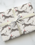 Gift wrapped in zebra-patterned paper with a white ribbon on a marble surface