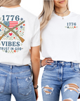woman wearing a white t-shirt with patriotic design crossed muskets floral adorned with a betsy ross flag trust in god text front and back views