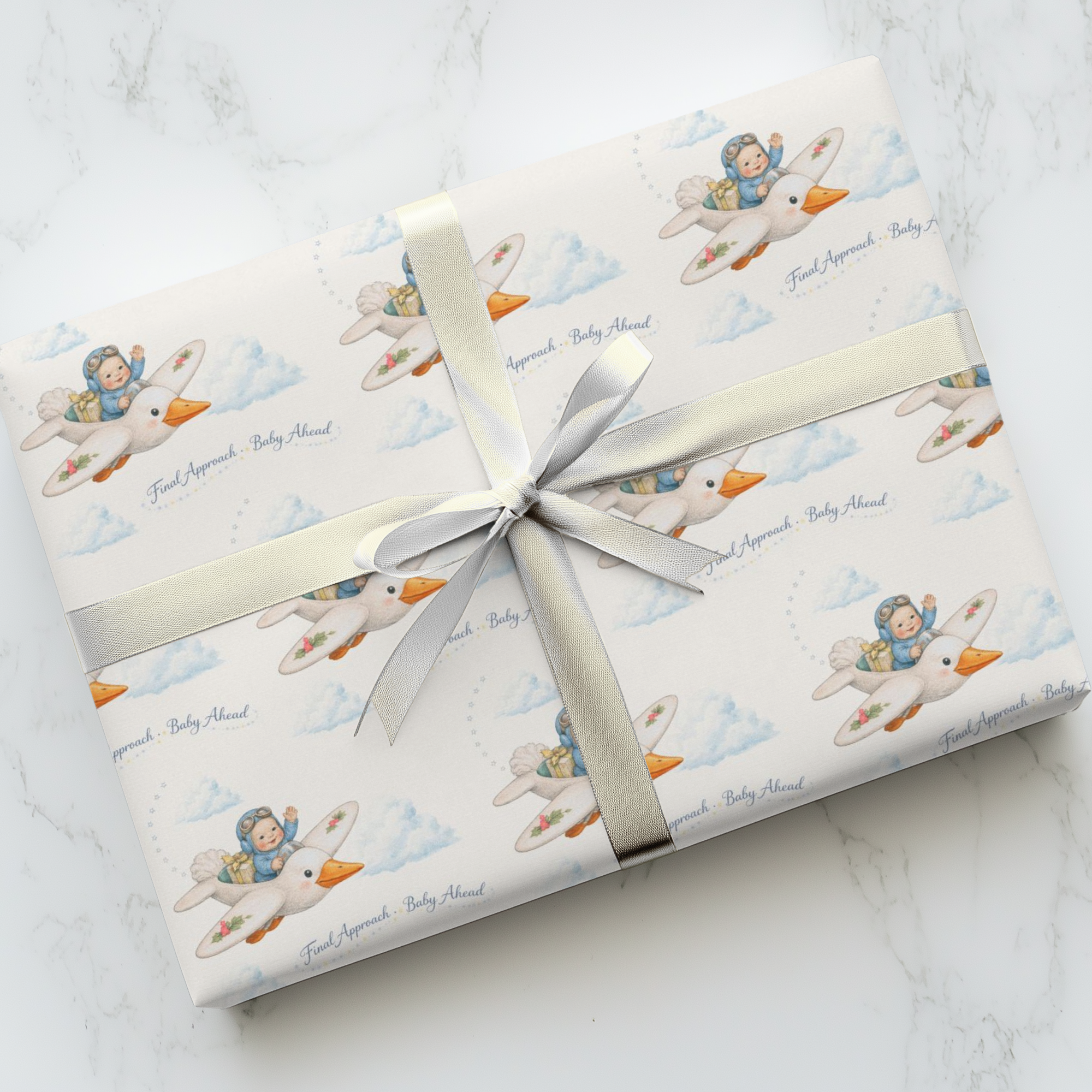 Gift wrapped in baby-themed paper with a white ribbon on a marble surface
