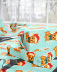 french bulldog christmas wrapping paper with golden dog in red hat and teal bow on aqua background with stars