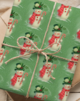 Gift box wrapped in green paper with snowman pattern on a wooden surface