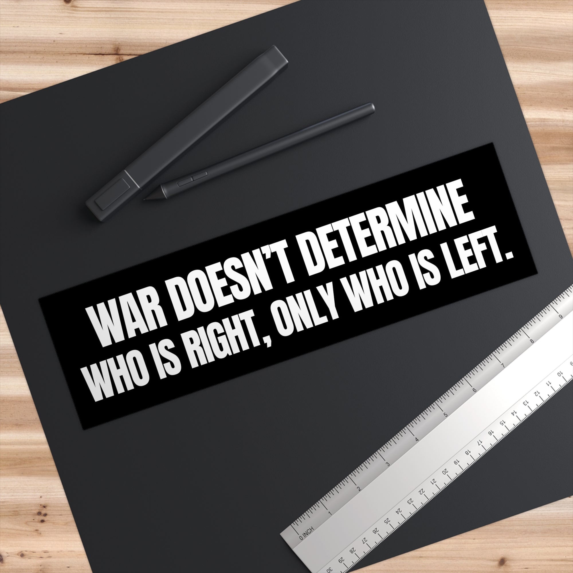 Black mat with a quote sticker and stationery on a wooden surface