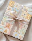 Baby quilt patchwork wrapping paper with teddy bears moons and nursery motifs wrapped gift with ribbon.