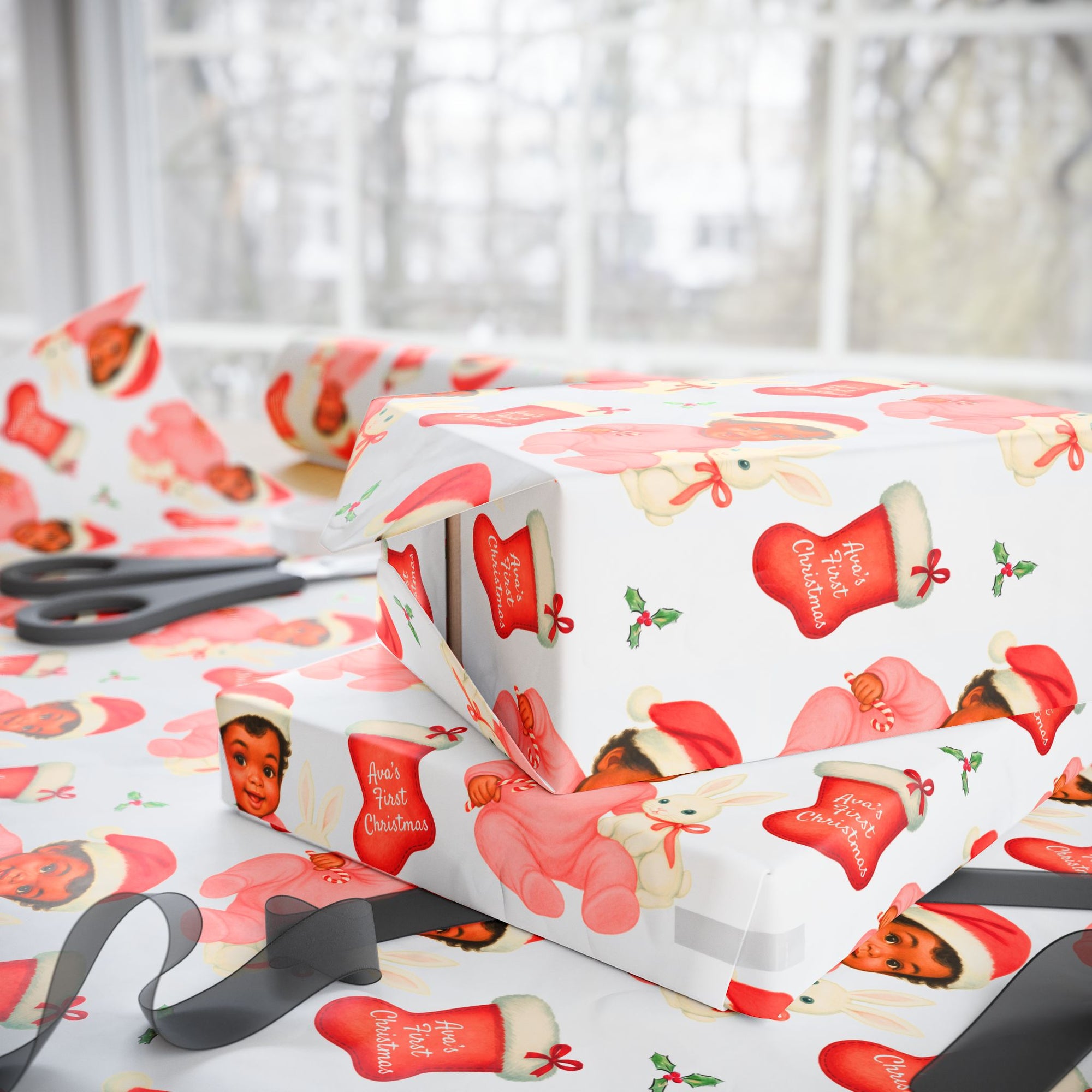 Christmas-themed wrapping paper that includes a african american baby with santa hat and a personalized stocking on a table with scissors on a white surface
