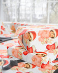 Christmas-themed wrapping paper with brunette baby in a Santa hat