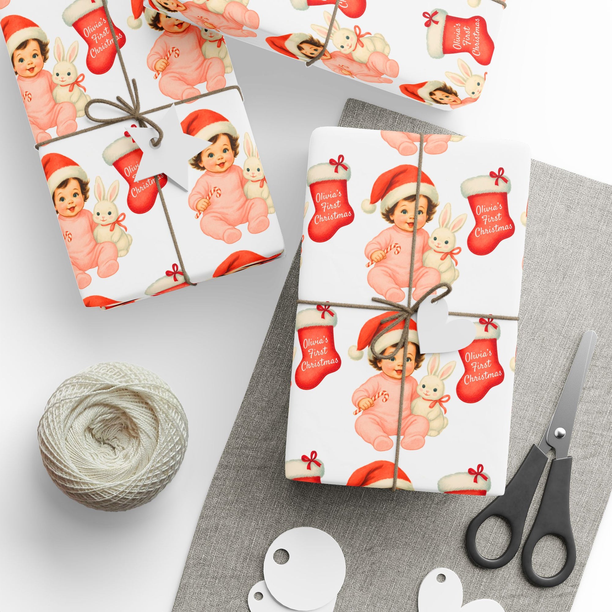 Christmas gifts wrapped in a babys first christmas wrapping paper with a brunette baby girl in a santa cap holding a bunny.