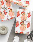 Christmas gifts wrapped in a babys first christmas wrapping paper with a brunette baby girl in a santa cap holding a bunny.