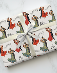 Gift wrapped in vintage-style dance-themed paper featuring couples in formal attire ballroom dancing with a white ribbon on a light background.