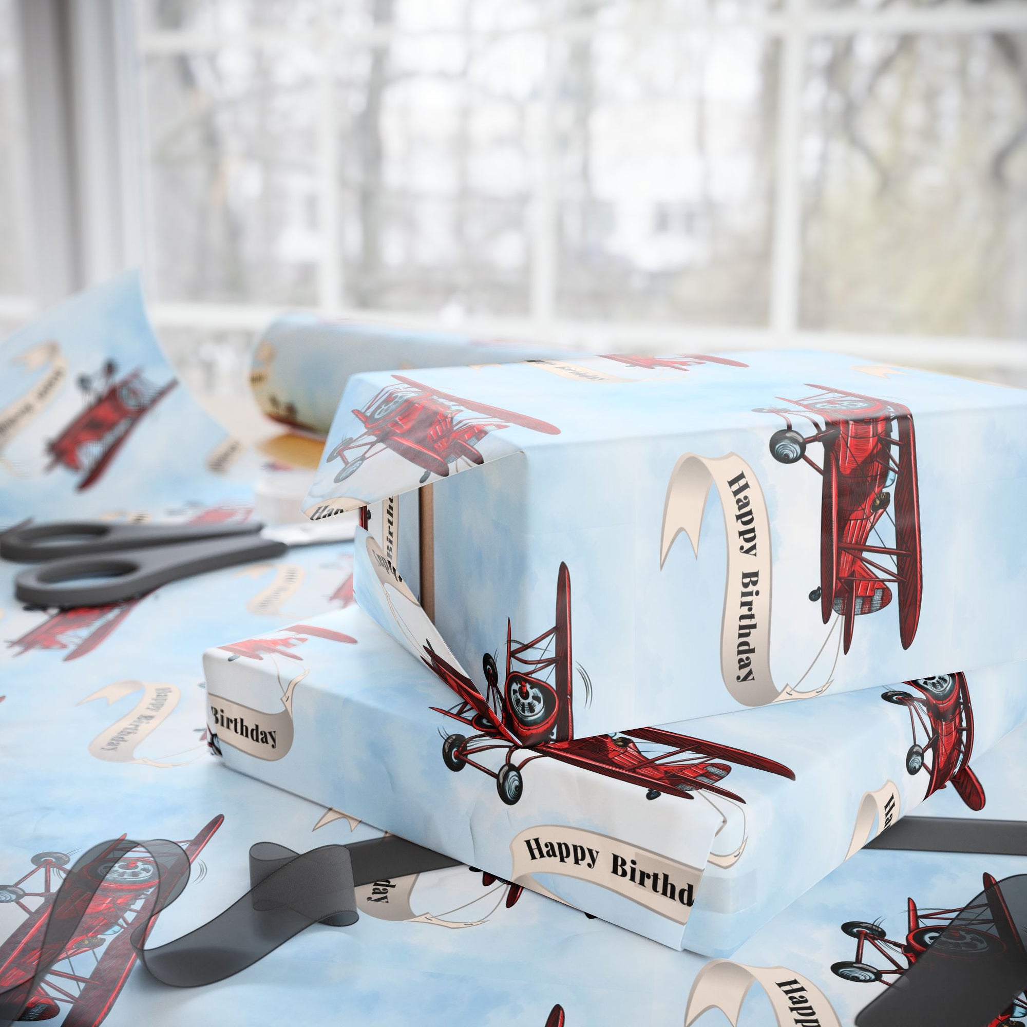 Wrapping paper featuring a classic red vintage biplane towing a cream-colored banner that reads “Happy Birthday”
